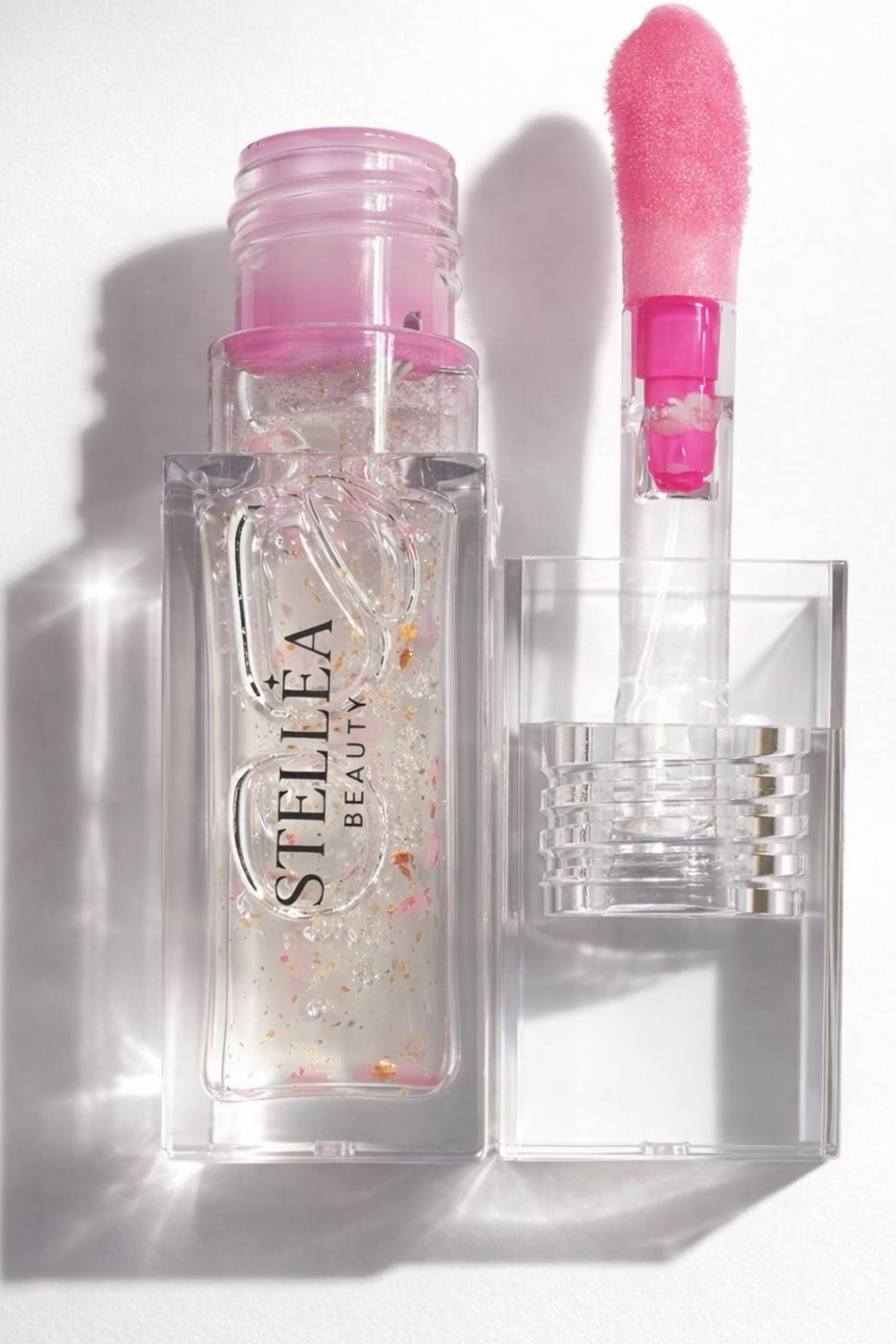 Huile à lèvres brillante STELLEA Amore en flacon transparent avec texture dorée nourrissante effet légèrement rose.